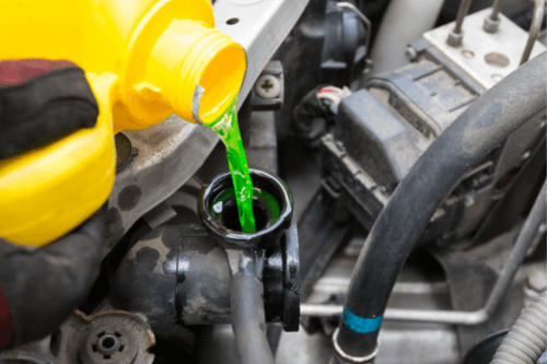 3 Signs You Just Might Have a Coolant Leak In Kenner LA with CAMS Automotive close up image of mechanic pouring coolant into car