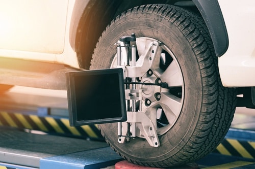Improve Your Ride with Regular Wheel Alignments in Kenner LA with CAMS Automotive image of alignment machine connected to front tire of car