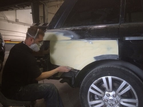 Repairing a Car After a Collision Accident | CAMS Automotive in Kenner, LA. Image of a car body specialist doing finishing work on a dent of a car.