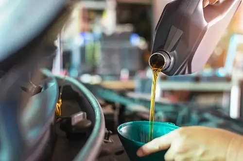 New Year, New Oil: Does New Oil Make a Difference? | CAMS Automotive in Kenner, LA. Image of a mechanic’ shand in the act of pouring fresh oil to a car engine.