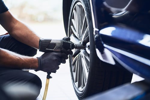 Tire Repair & Services in Kenner, LA | CAMS Automotive. Image of a tire mechanic removing a car tire with pneumatic wrench in an auto repair shop.