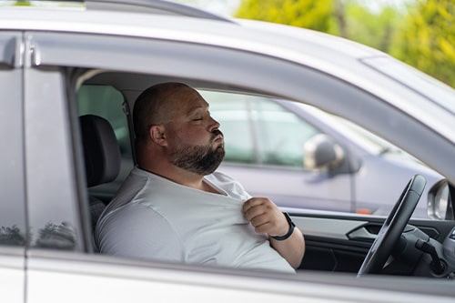 Exhausted male driver sitting inside car in hot weather. Concept image of “Beat the Heat: How to Keep Your Car Cool in Kenner, LA” | CAMS Automotive.