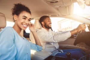 Family Travel Car Safety Tips | CAMS Automotive in Kenner, LA. Young african american couple driving in car smiling.