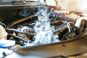Overheating engine with visible steam rising from under the hood signaling for an engine repair and auto repair in Kenner, LA at CAMS Automotive.
