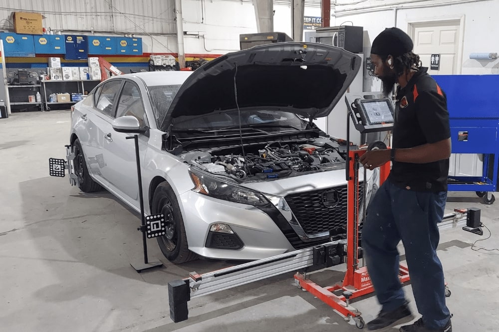 ADAS Calibration, auto repair Kenner, LA by CAMS Automotive. A technician uses advanced alignment and calibration equipment on a silver sedan, ensuring precise sensor and camera recalibration for safety and driver-assistance systems.