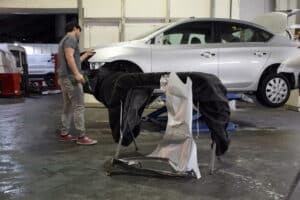 Collision repair process in Kenner, LA, at CAMS Automotive. Image of a vehicle undergoing collision repair in the shop, with damaged body panels removed and replacement components prepared for installation, highlighting professional auto body repair, structural restoration, and quality workmanship to return vehicles to pre-accident condition.