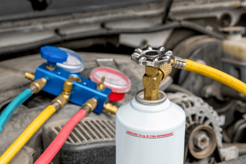 Car A/C repair in Kenner, LA by CAMS Automotive. Image of R-134a refrigerant canister and manifold gauges connected under the hood, highlighting professional A/C service to restore cooling efficiency during summer heat.